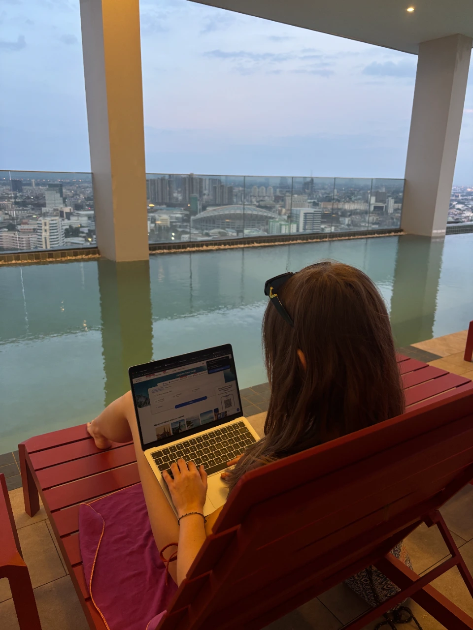 Dziewczyna przy laptopie na basenie, na dachu w Bangkoku