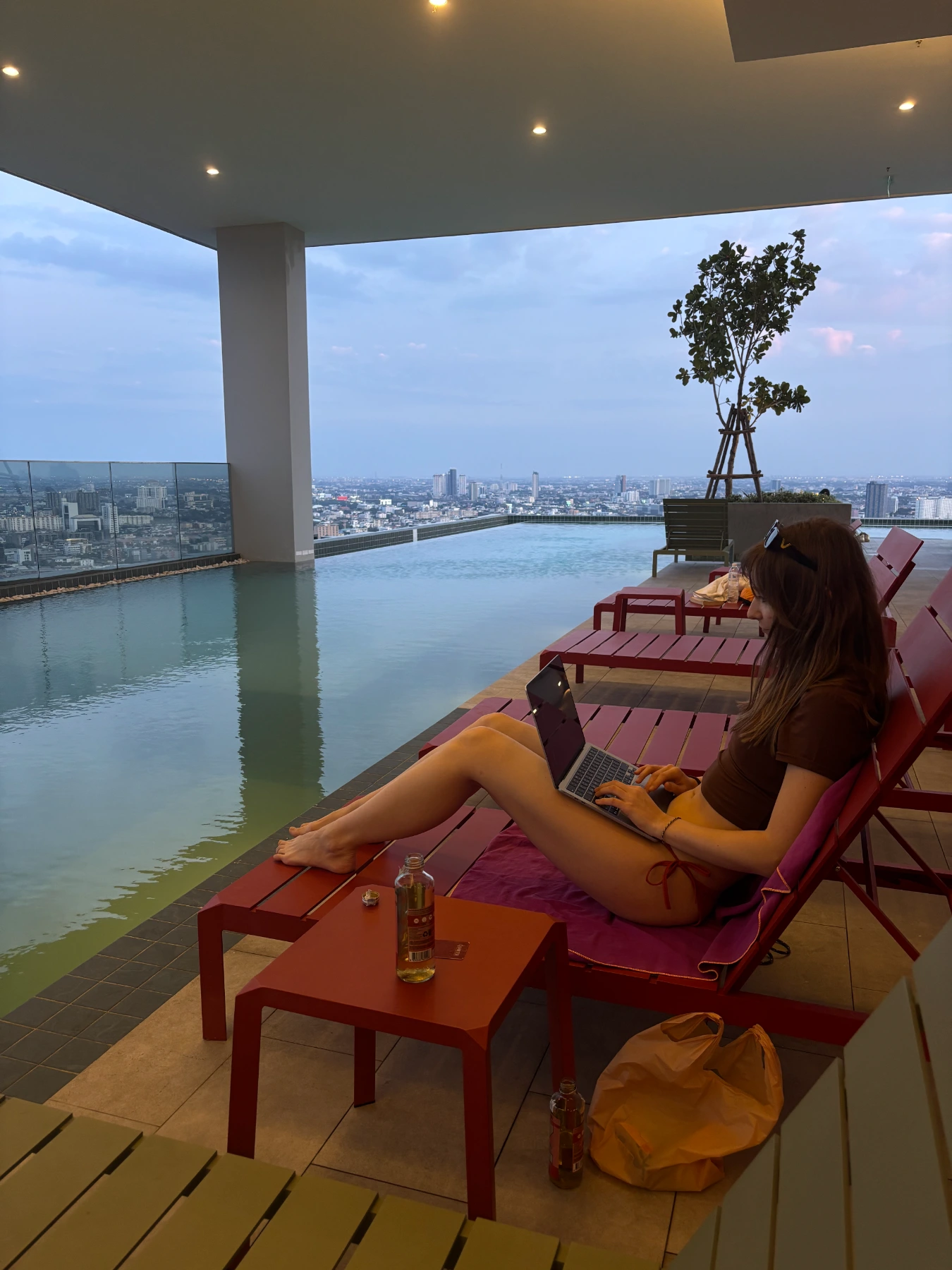Dziewczyna przy laptopie na basenie, na dachu w Bangkoku